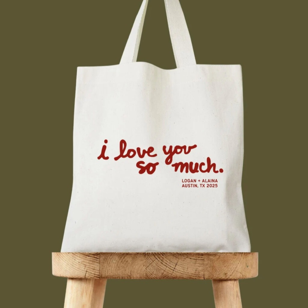 white cotton tote bag with red writing saying "i love you so much" and the couples name and date